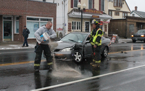PAUL SQUIRE PHOTO | A Jamesport firefighters spreads absorbent material to soak up vehicle fluid at the scene of a two-vehicle crash Monday afternoon.