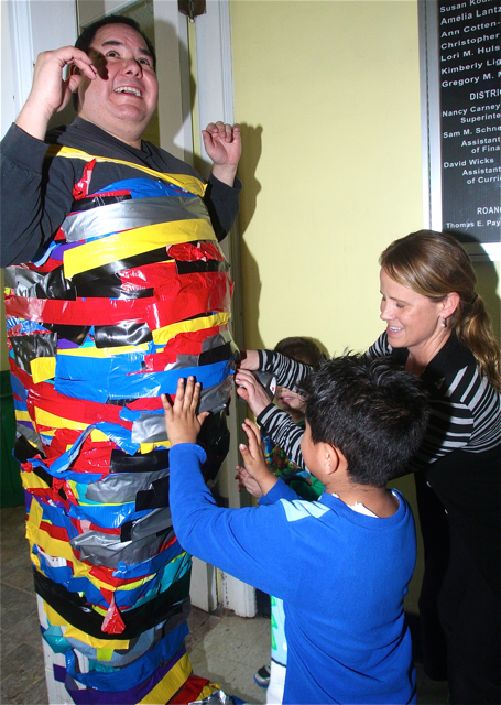 Reading teacher Corrine Arrasate helps kindergartners Rudy Dejesus Guiterrez (left) and Rudy Garcia apply tape. Barbaraellen Koch photo