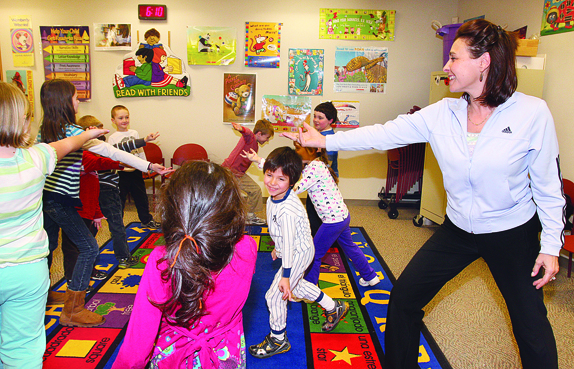 Fitness instructor and yoga teacher Beth Hagedorn of Holtsville leads a group of youngsters in pretending to throw out Spiderman webs during a 'Fit Kids' session at Riverhead Free Library Friday night.