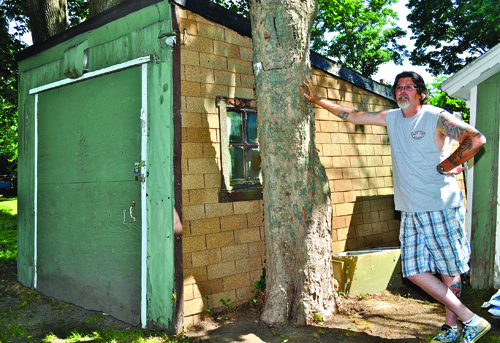 GIANNA VOLPE PHOTO | Richard Hardt next to the garage he said his great-grandfather Mervin Baker assembled with lumber left over from the building of Brecknock Hall in Greenport. GIANNA VOLPE PHOTO | Richard Hardt next to the garage he said his great-grandfather Mervin Baker assembled with lumber left over from the building of Brecknock Hall in Greenport.