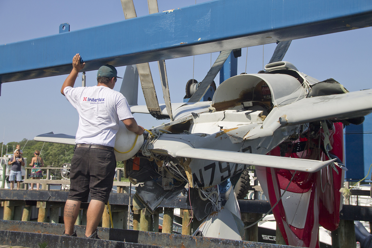 A Mattituck Inlet Marina employee helps guide the crashed experimental plane out of the water Monday afternoon.  (Credit: Paul Squire)