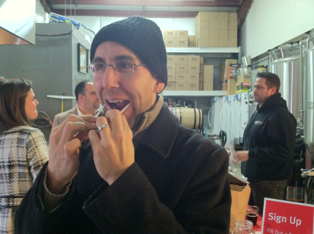 Bill Faulk of Manorville puts himself on the national list of potential bone marrow donors by swabbing his cheeks at Saturday's event with Joseph Latini (background, left) and organizer Patrick Gaeta. (Credit: Michael White)