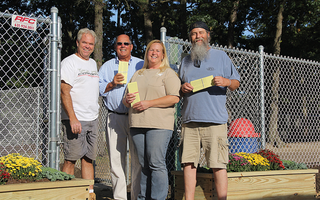 Riverhead Move the Animal Shelter volunteers (from left) Richie Cox, Fred McLaughlin, Denise Lucas and Lindsay Reeve at Stotzky Park's Duke Dog Park Friday. They're holding tickets to the group's three-year anniversary benefit at Suffolk Theater planned for November. (Credit: Carrie Miller)